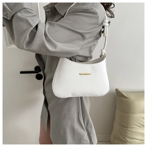 Detail of white leather crescent underarm bag with gold metal trim and slim shoulder strap