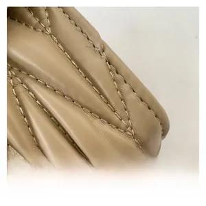 Détail des coutures en V et texture cuir beige-gris sur le sac à bandoulière