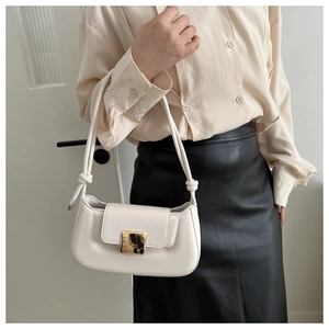 Detail of a minimalist white shoulder bag with a gold square lock and knotted strap detail