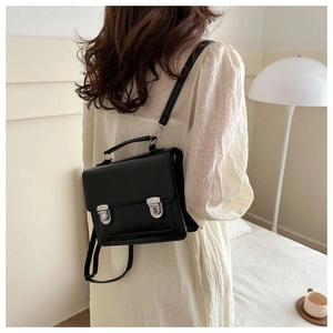 Detail of black vintage satchel bag with silver metal buckles on a model's shoulder