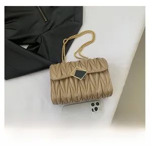 Détail du sac à bandoulière en cuir plissé beige avec chaîne dorée et fermoir géométrique