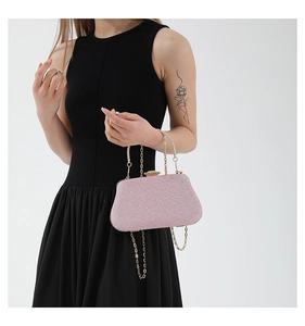 Pochette da sera rosa glitterata con chiusura a strass e catena dorata tenuta da una donna