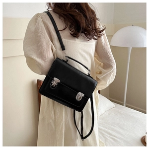 Detail of black vintage PU leather satchel bag with silver buckles and a top handle