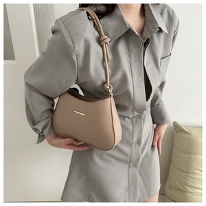 Detail of elegant khaki leather underarm bag with gold hardware and knot strap design