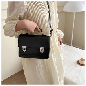 Détail du sac bandoulière en cuir noir mat avec boucles argentées et poignée
