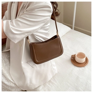 Detail of a dark brown vintage baguette bag featuring slim straps and gold hardware