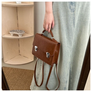Detail of vintage brown PU leather satchel with silver buckles and handle texture