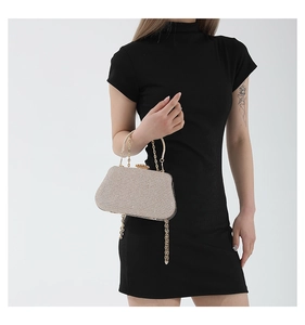 Dettaglio della borsa clutch champagne con chiusura a gemma e manico a catena