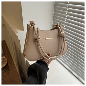 Dettaglio borsa a spalla beige con fibbia dorata e tracolla con nodi decorativi
