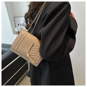 Detail of trendy crossbody bag with V-shaped quilting and golden tassel chain strap