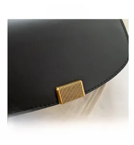 Macro detail of golden rectangular lock on premium black matte leather shoulder bag