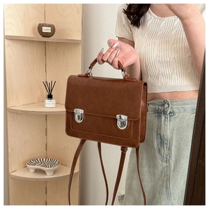 Detailed side view of a brown vintage messenger bag with silver buckles and handle