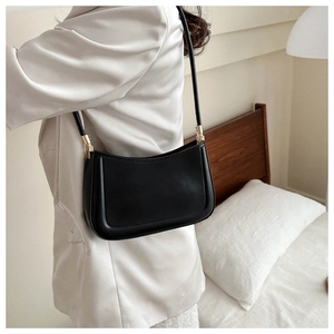Detail of black vintage crescent shoulder bag with golden hardware on grey blazer