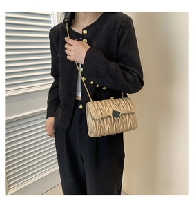 Détail du sac bandoulière plissé beige avec boucle métallique et chaîne dorée élégante