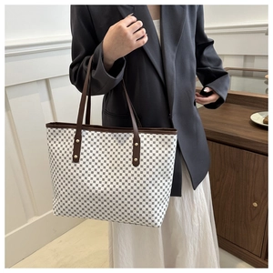 Chic tote bag with black geometric print and brown handles featuring metallic studs