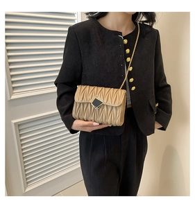 Détail de la texture cuir plissé beige clair et fermoir doré du sac à chaîne