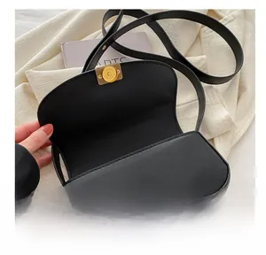 Detailed close-up of the black PU leather handbag featuring a round magnetic metal clasp