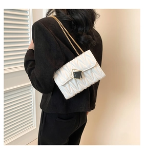 Détail d'un sac blanc matelassé avec chaîne dorée porté par un mannequin en lumière douce