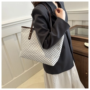 Detailed view of the patterned tote bag with leather straps and rivet accents shown on a model