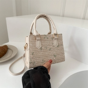Woven straw handbag with floral embroidery and white faux leather straps for summer beach
