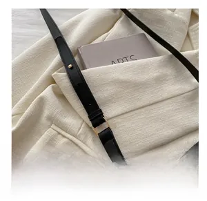 Detail of black PU leather strap with golden metal buckle on tweed jacket background