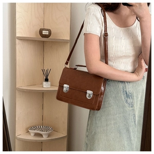 Détail d'un sac besace vintage marron avec double boucles en métal argenté et bandoulière