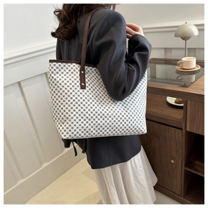 Close-up of stylish polka dot tote bag with leather straps and metal rivets on shoulder