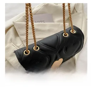 Close-up of black heart-quilted leather bag with golden heart clasp and chain strap