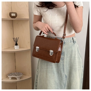 Détail d'un sac à bandoulière vintage marron avec boucles argentées porté par un mannequin