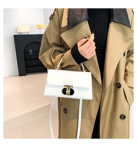 Dettaglio della borsa Kelly bianca in pelle PU con chiusura dorata su un trench coat