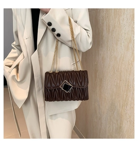 Détail d'un sac à bandoulière matelassé marron foncé avec fermoir géométrique