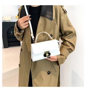 Borsa a tracolla bianca con fibbia dorata indossata con un trench kaki alla moda