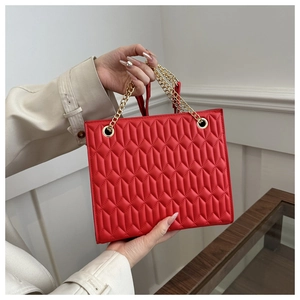 Detail of red quilted plaid shoulder bag with golden chain straps and soft texture