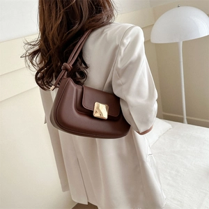 Brown leather shoulder bag with gold square buckle and knotted strap on white satin blazer