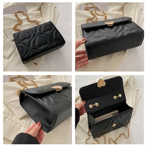 Detail view of black heart quilted crossbody bag with gold chain strap and interior space