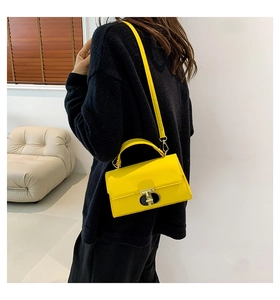 Dettaglio di una borsa a tracolla in pelle giallo acceso con chiusura girevole in metallo