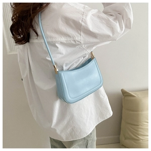 Detailed shoulder view of a light blue minimalist baguette bag worn over a white shirt