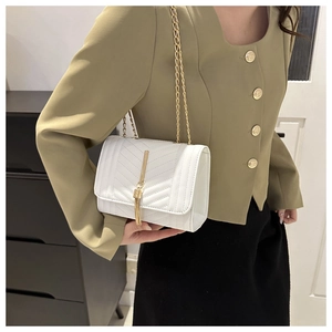 Detail of white quilted chain bag with gold fringe tassel on a female model