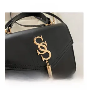 Close-up of black textured leather bag with gold interlocking logo and tassel detail