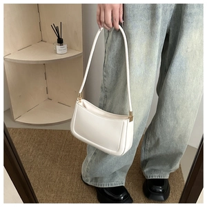 Detail of minimalist creamy white PU leather shoulder bag with gold hardware and slim handle