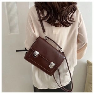 Vue arrière détaillée d'un sac messager vintage marron foncé avec boucles en métal argenté
