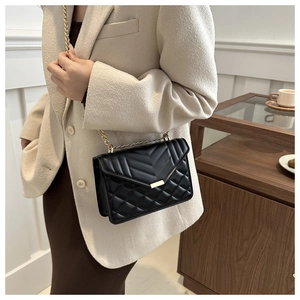 Side view of black quilted chain bag on model showing elegant drape and V-pattern texture