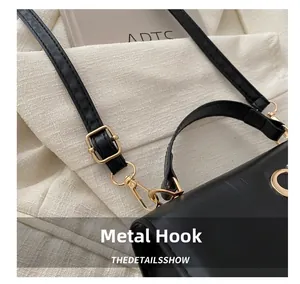 Close-up of bright gold metal hook and adjustable shoulder strap on black PU leather bag