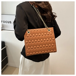 Detail of brown quilted leather bag featuring gold chain strap and textured diamond pattern