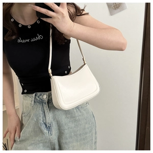 Detail view of white matte leather shoulder bag with gold hardware on female model