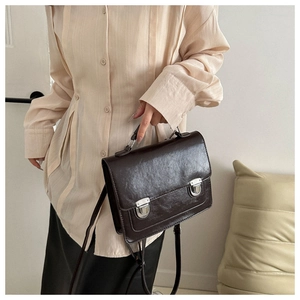 Détail du sac bandoulière vintage marron foncé en similicuir avec double boucle métal