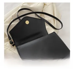 Detailed close-up of a black matte leather crossbody bag with a gold magnetic snap buckle