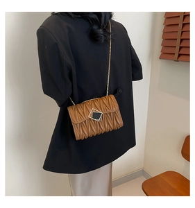 Détail de la texture en cuir matelassé marron et chaîne dorée sur ce sac bandoulière
