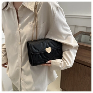 Détail du sac bandoulière noir avec matelassage cœur et fermoir doré en cœur