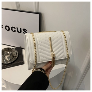 Detail view of white chevron quilted handbag with gold chain strap and metal tassel